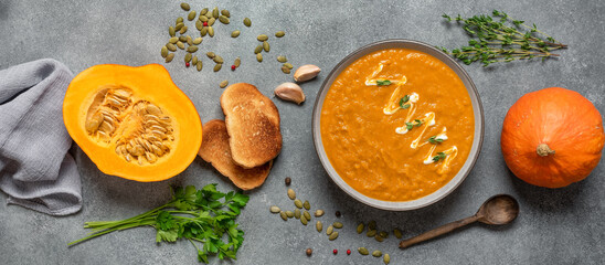 Homemade pumpkin cream soup with toast. Cozy dinner. Top view, banner. Thanksgiving concept.