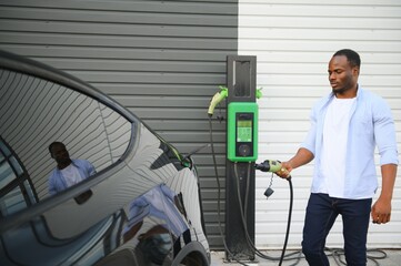 Man Plugging In Electric Car Outside Office In Car Park Charging