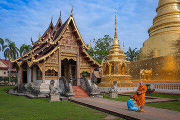 Beautiful women in Thai dress make merit offer food with monks to Asian traditional Buddhism at Wat Phra Singh Woramahawihan Temple tourist attraction and famous place in Chiang Mai, Thailand.