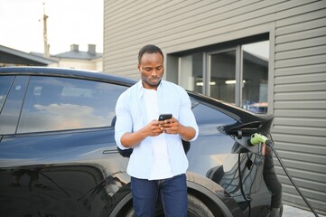 African American man charging his electric car.