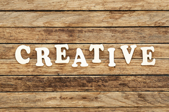 The word Creative written on wood letters on wooden background, top view.