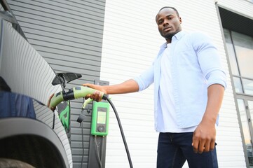 African American man charging his electric car.