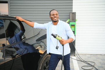 African American man charging his electric car.
