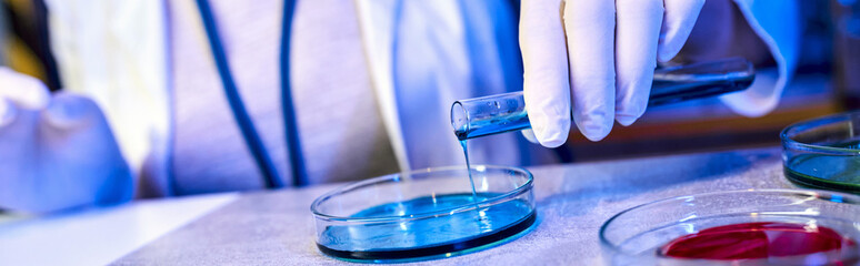 cropped view of scientist pouring liquid in petri dish, exploring alien life, banner