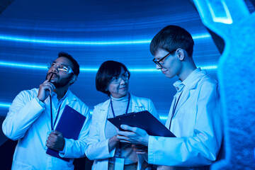 scientific creativity, indian scientist thinking near smiling colleagues in experimental center
