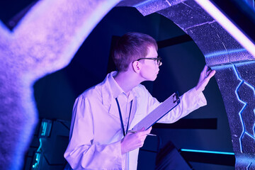 future technologies, young intern with clipboard examining new equipment in science center