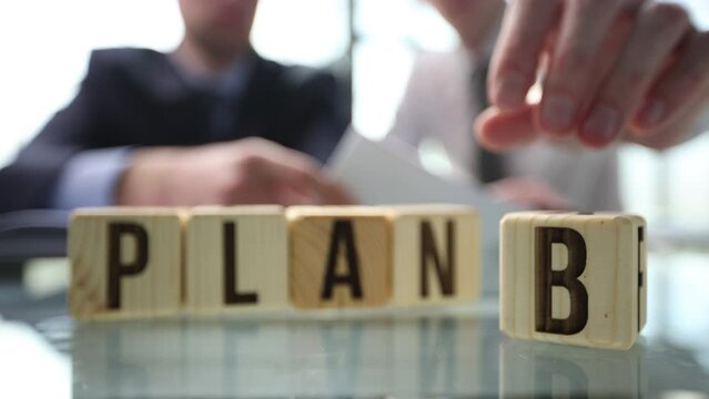 Businessman hand flipping wooden cube blocks with PLAN A change to PLAN B