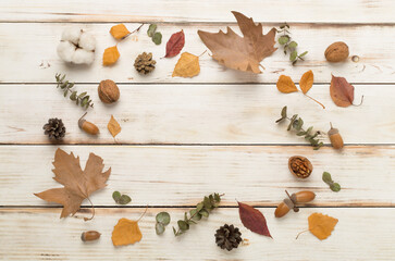 Autumn leaves with decor on wooden background, top view