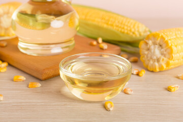 Corn oil with fresh cobs on wooden table