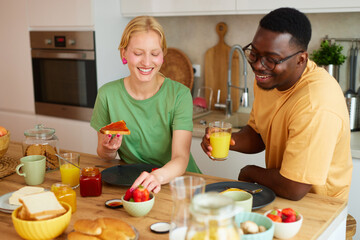 Multiracial couple enjoying breakfast together at home