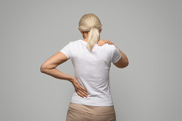 Unrecognizable mature blonde woman suffering neck and back pain - obrazy, fototapety, plakaty