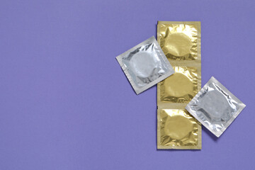 Condom packages on violet background, flat lay and space for text. Safe sex