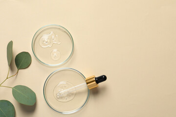 Petri dishes with samples of cosmetic oil, pipette and eucalyptus leaves on beige background, flat...