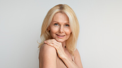 Naklejka premium Portrait of beautiful middle aged woman with smooth skin posing over grey background, panorama, free space