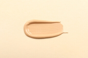 Smear of skin foundation on beige background, top view