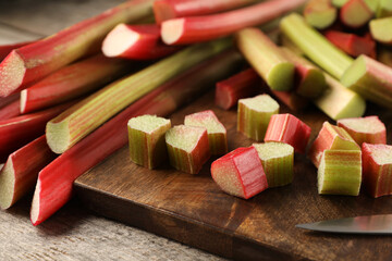 Many cut rhubarb stalks on wooden table, closeup