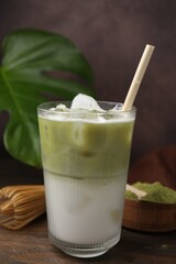 Glass of tasty iced matcha latte on wooden table
