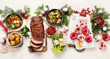 Fototapeta na wymiar Delicious Christmas themed dinner table with roasted meat, appetizers and desserts. Holiday concept.