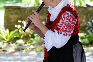 Senior woman playing the recorder in traditional clothes