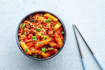 Rabokki, tteokbokki or topokki with ramen, Korean street food, spicy rice cakes in red pepper gochujang sauce, overhead flat lay shot with chopsticks