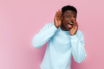 curious african man in blue sweater eavesdrops and tells secret on pink isolated background, the...