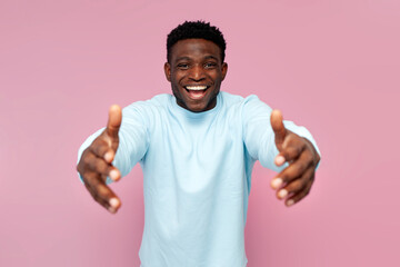 african american man in blue sweater holds empty hands in front of him and hugs you on pink isolated background