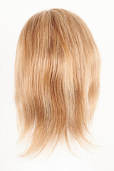 Fototapeta premium Natural looking blonde fair wig on white mannequin head. Middle length hair cut on the plastic wig holder isolated on white background, back view