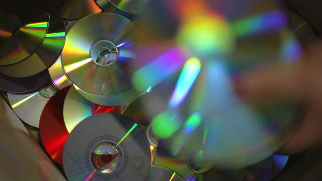 Close-up top view CD-ROM discs falling in box in slow motion. Closeup trash for recycling indoors