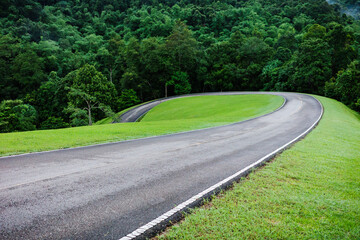 Local curved road on hill slope inside tropical rainforest.