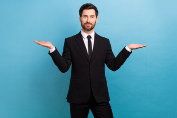 Photo of happy smiling clerk wear black tuxedo comparing arms empty space isolated blue color...
