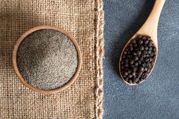 Ground black pepper with grains of black pepper on dark background
