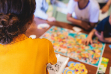 Fototapeta premium Process of playing board game and having fun with friends and family indoors, board game concept, group of kids children play board games at the table, roll the dice