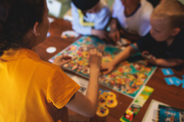 Process of playing board game and having fun with friends and family indoors, board game concept, group of kids children play board games at the table, roll the dice