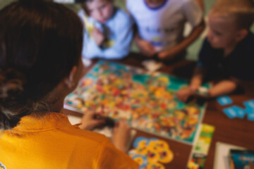 Process of playing board game and having fun with friends and family indoors, board game concept, group of kids children play board games at the table, roll the dice