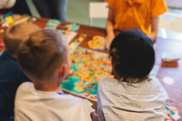 Process of playing board game and having fun with friends and family indoors, board game concept, group of kids children play board games at the table, roll the dice