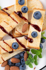 Toasts with  blueberries and almonds in  white plate  clouseup top view