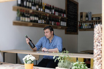 professional wine store manager organizing bottles and orders using pad
