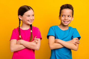 Photo of cunning cute preteen schoolkids dressed t-shirts arms folded looking each other isolated...