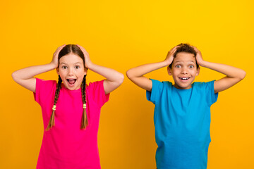 Fototapeta na wymiar Photo of astonished funky schoolkids hands touch head open mouth unbelievable isolated on yellow color background