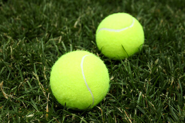 Two tennis balls on green grass, close up