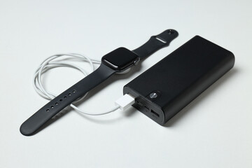 Powerbank, cord and smart clock on white background