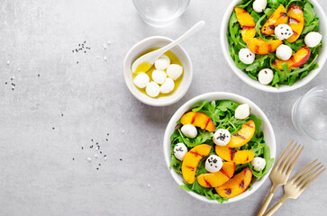 Grilled Peach Salad with Arugula and Mozzarella on Bright Concrete Background