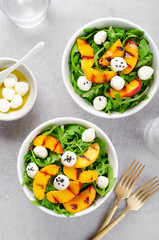 Grilled Peach Salad with Arugula and Mozzarella on Bright Concrete Background