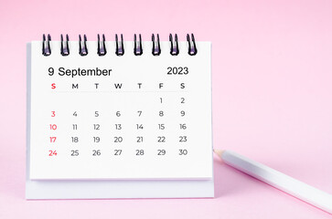 The September 2023 and pencil desk calendar on pink color background.