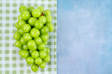 The Japanese Shine Muscat Grape on tablecloth on wooden blue background with copy space for your text.