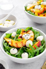 Grilled Peach Salad with Arugula and Mozzarella on Bright Concrete Background
