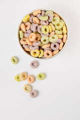 Colored flavored cereal rings in white bowl top view