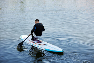 Minimal portrait of adult man with disability riding sup board enjoying water sports outdoors in nature, copy space