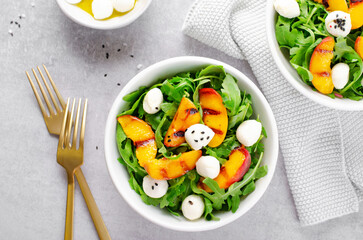 Grilled Peach Salad with Arugula and Mozzarella on Bright Concrete Background