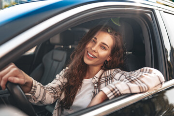 Fototapeta na wymiar Young smiling woman driving a car in the city